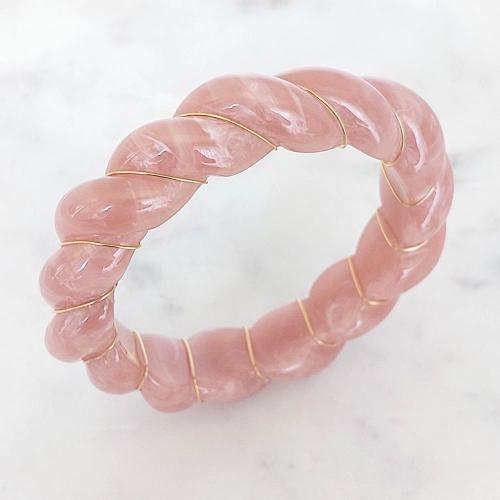 Bracelet jonc torsadé en résine coloris rose et recouvert d'un liseret en acier inoxydable trempé dans un bain doré